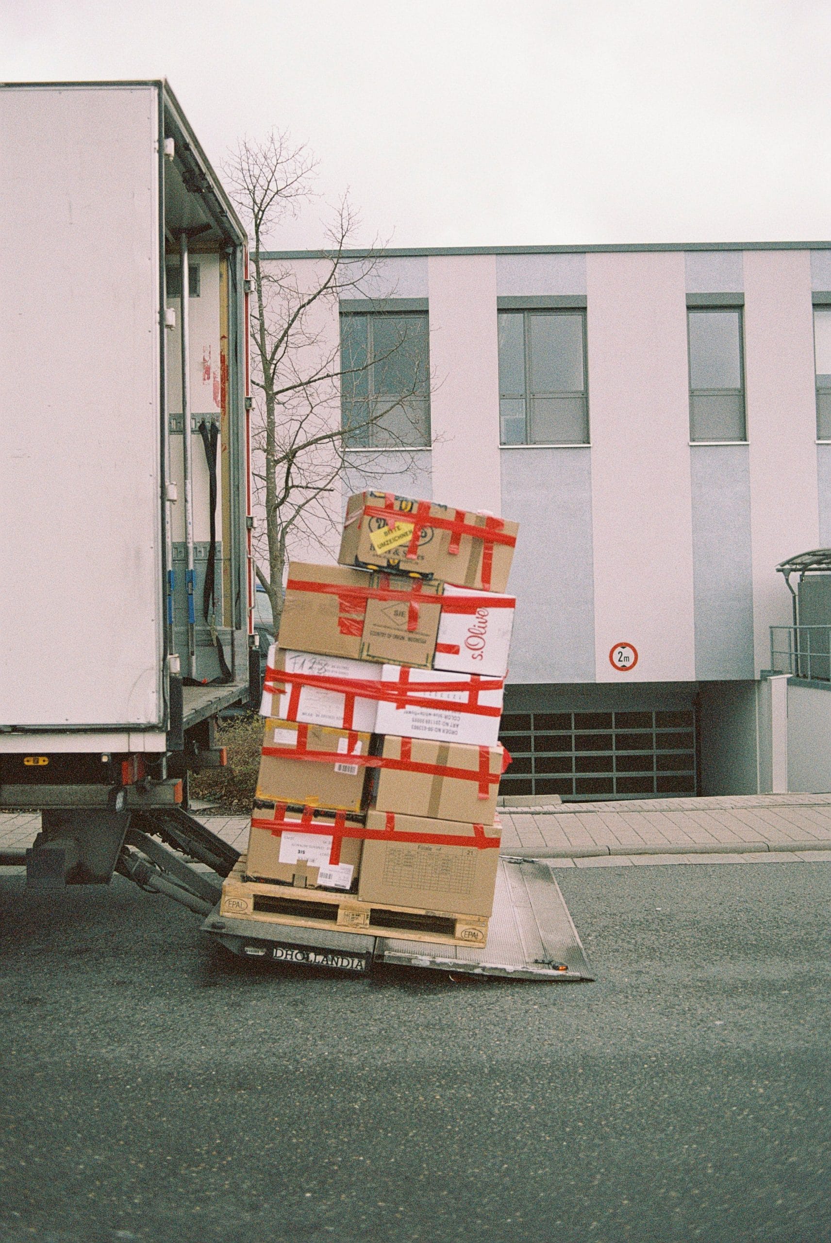 Stack of cardboard boxes on a delivery truck liftgate, illustrating cross-border e-commerce logistics and a hybrid fulfillment model.